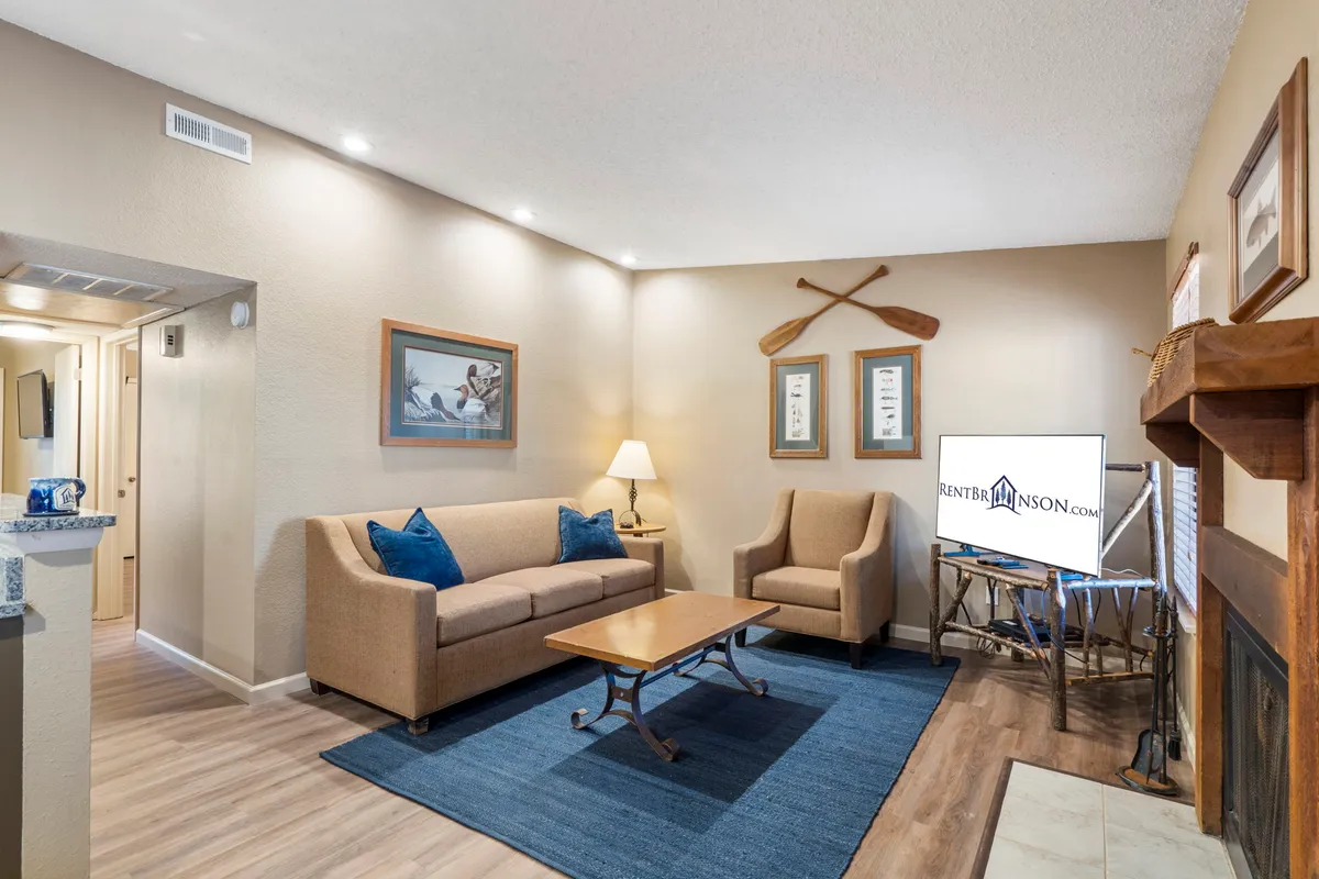 A cozy bedroom interior featuring a bed with a green throw blanket, moose painting above the headboard, and soft, inviting lighting. The scene exudes warmth and comfort, making it a welcoming space for guests and their pets.