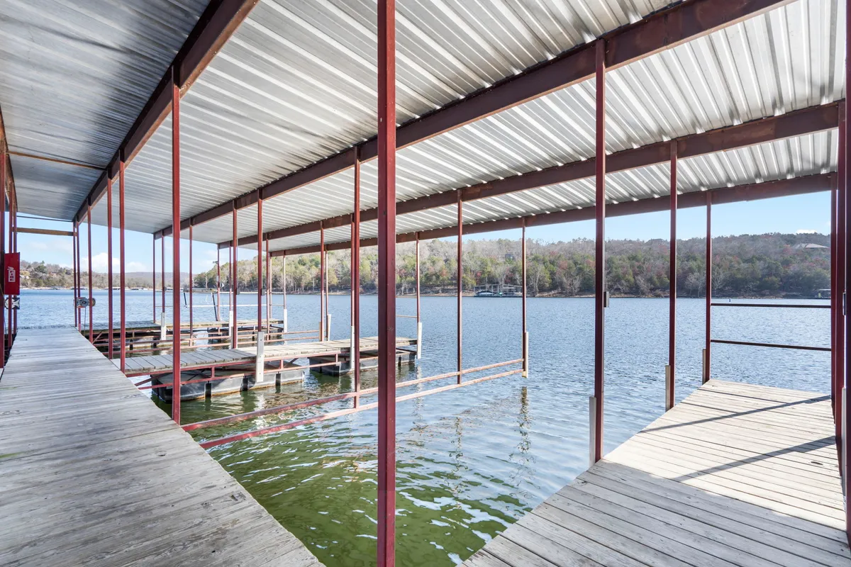 This image captures a peaceful dock surrounded by calm water and lush trees. Soft lighting suggests either early morning or evening, setting a tranquil mood perfect for quiet reflection or a romantic stroll. The dock offers direct access to the serene lakeshore, inviting couples to linger and take in nature's beauty.