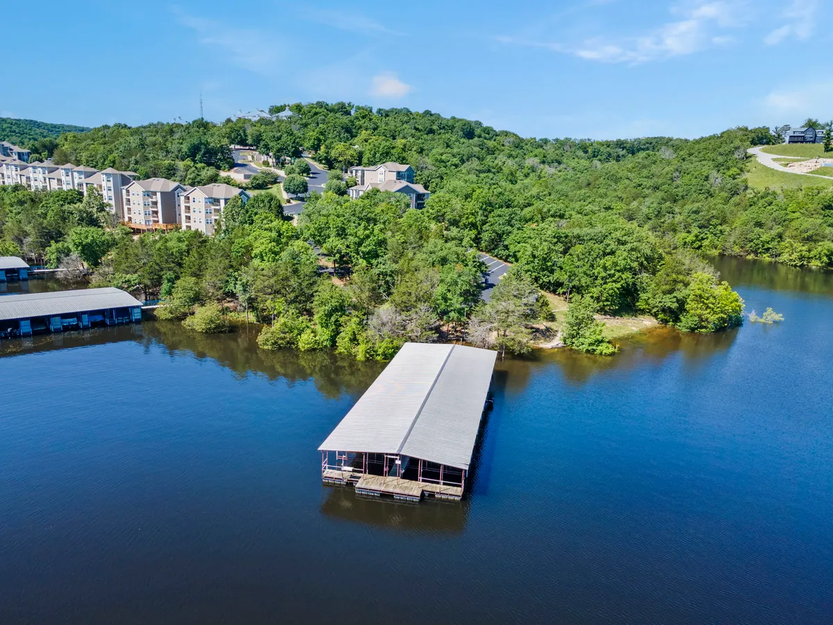A scenic lakeside view featuring a boat dock, calm waters, surrounding greenery, and apartments nestled on the hillside. The relaxed atmosphere and expansive view evoke the calm resort setting described in the section, emphasizing the beauty and accessibility of the outdoors for couples.